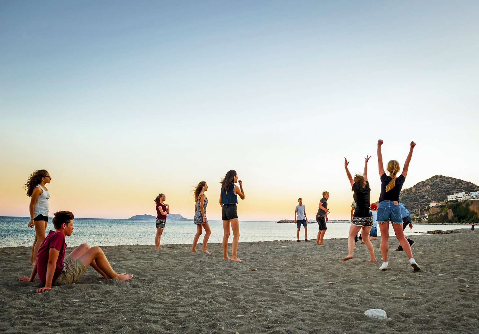 Kinder spielen am Strand bei Sonnenuntergang am Meer
