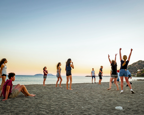 Kinder spielen am Strand bei Sonnenuntergang am Meer