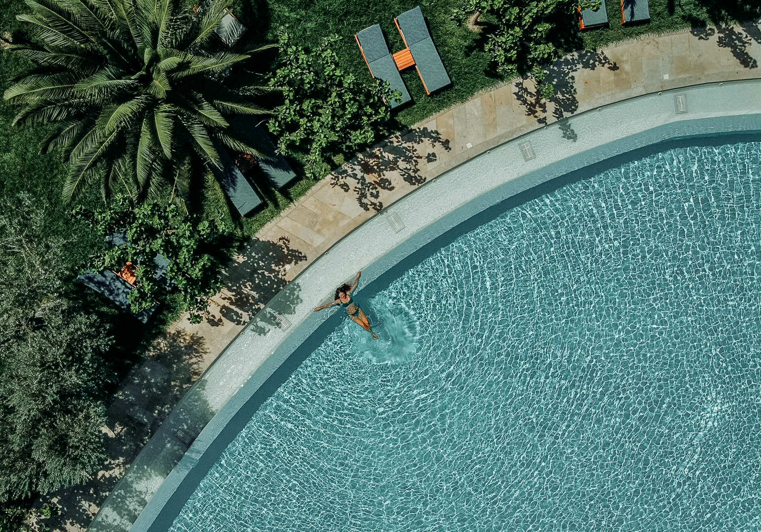 Luftaufnahme eines geschwungenen Pools mit Liegebereich