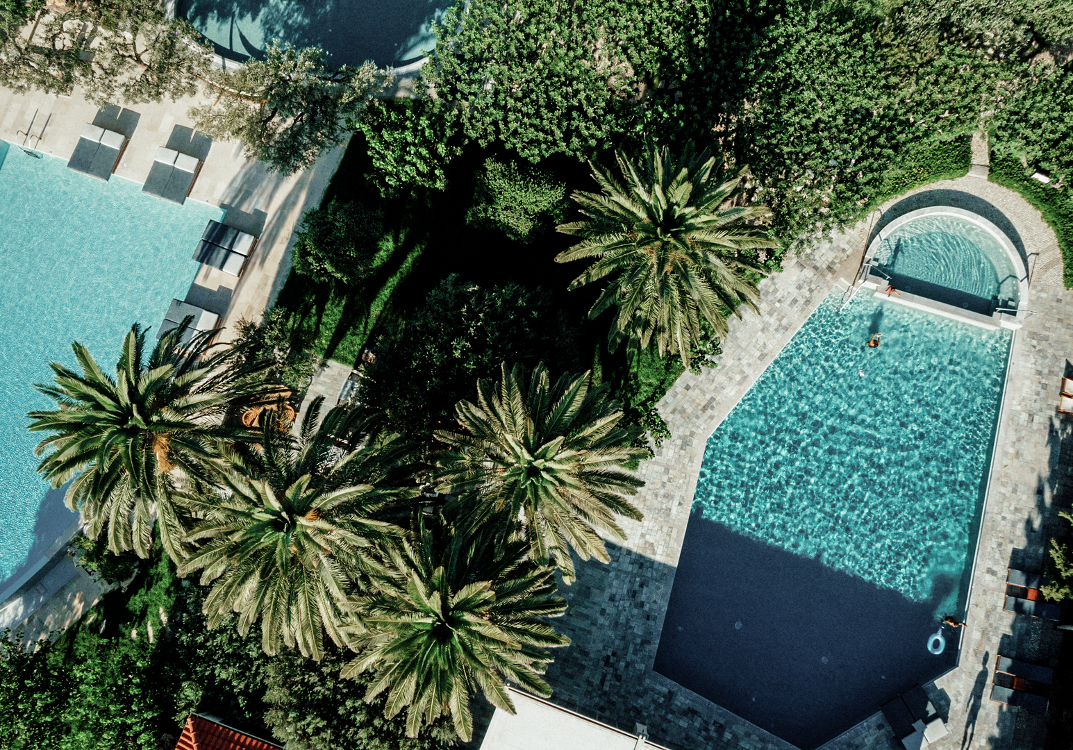 Luftaufnahme von Poollandschaft mit Palmen und Liegeflächen