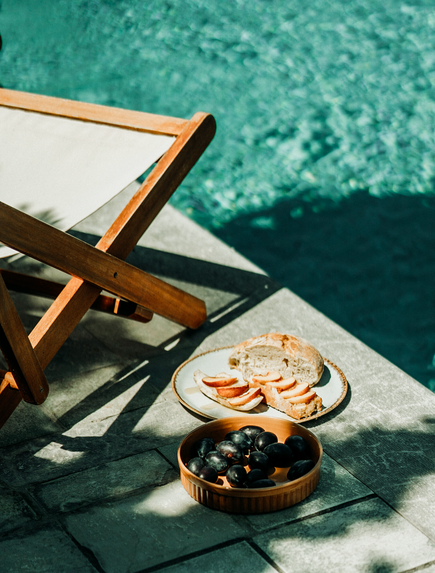 Frühstückstablett mit Kaffee und Gebäck am türkisblauen Poolrand