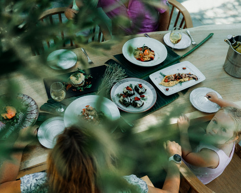 Frühstückstisch mit frischen Speisen im Grünen unter Bäumen