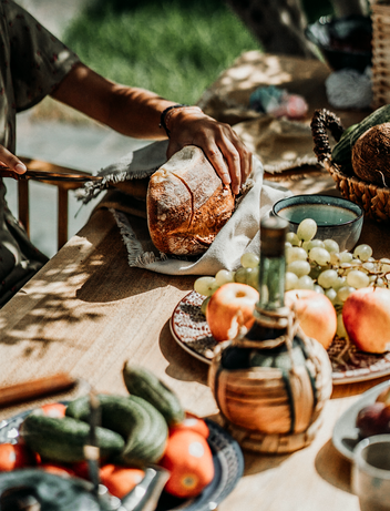 Frisches Brot wird auf einem sommerlich gedeckten Tisch geschnitten