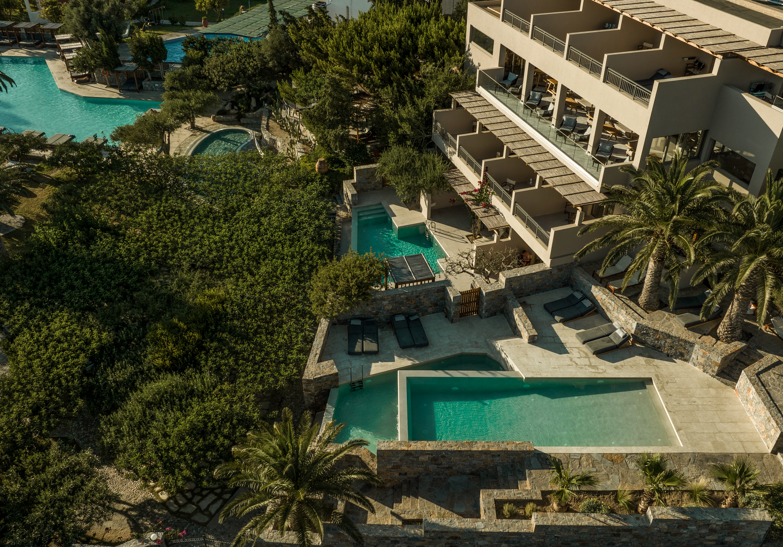 Luftaufnahme einer modernen Ferienanlage mit Pool und mediterraner Gartenlandschaft