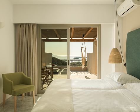 Schlafzimmer mit Doppelbett, grünem Sessel und Meerblick