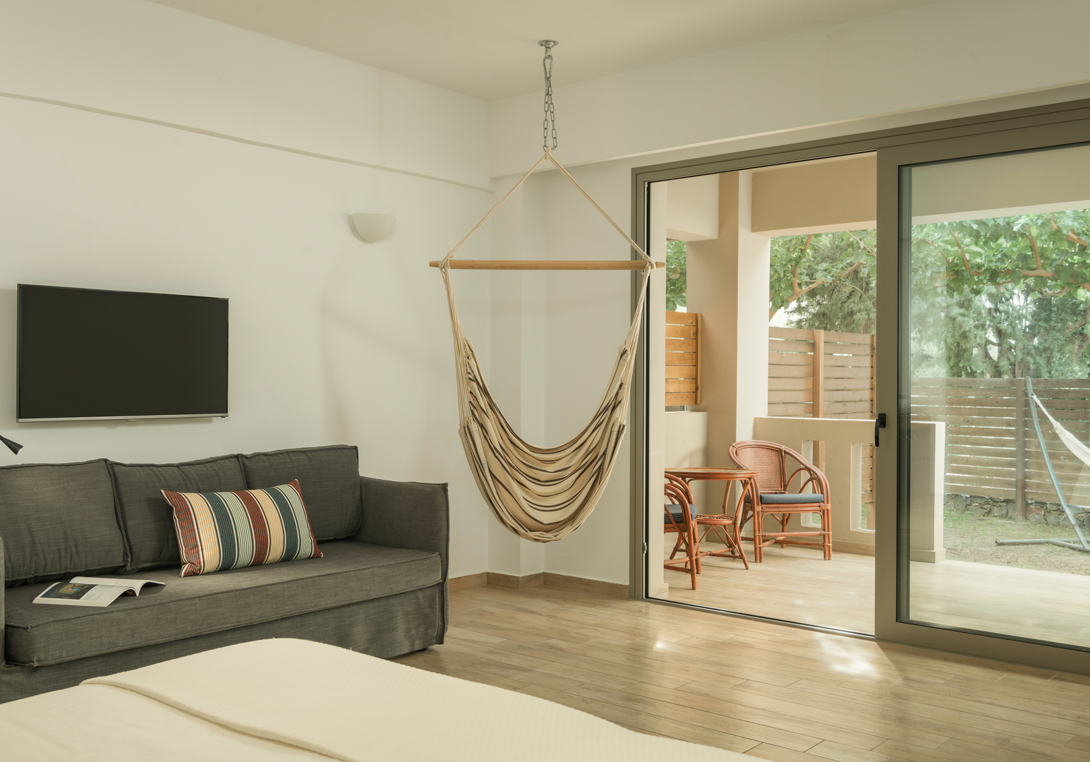Wohnbereich mit Sofa, TV und Terrasse mit Hängematte