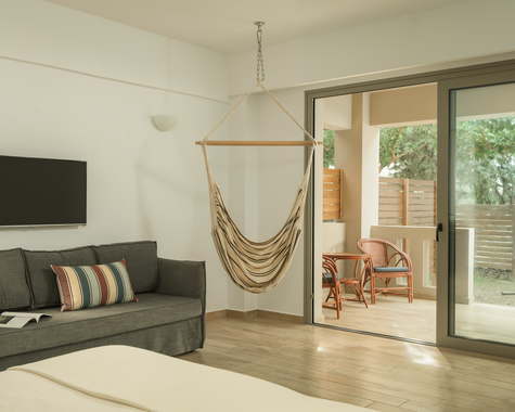 Wohnbereich mit Sofa, TV und Terrasse mit Hängematte