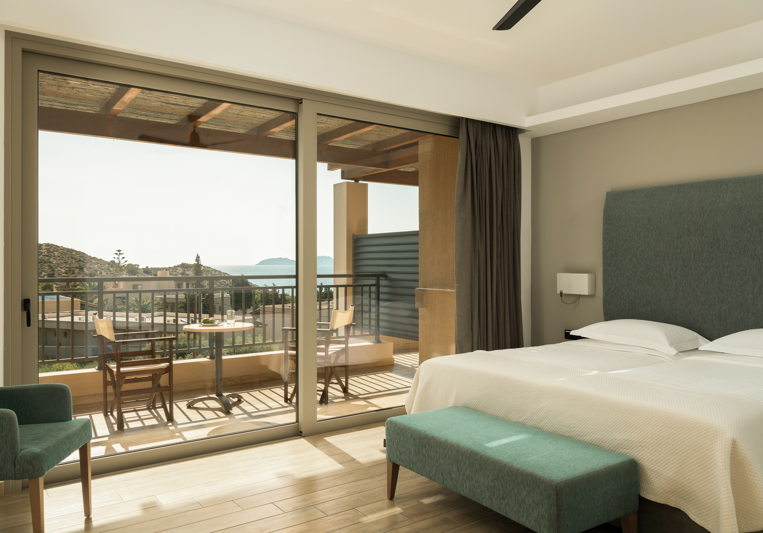 Schlafzimmer mit Doppelbett, türkisem Kopfteil und Balkon