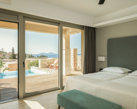 Doppelbett mit türkisem Kopfteil und Blick auf Pool und Meer