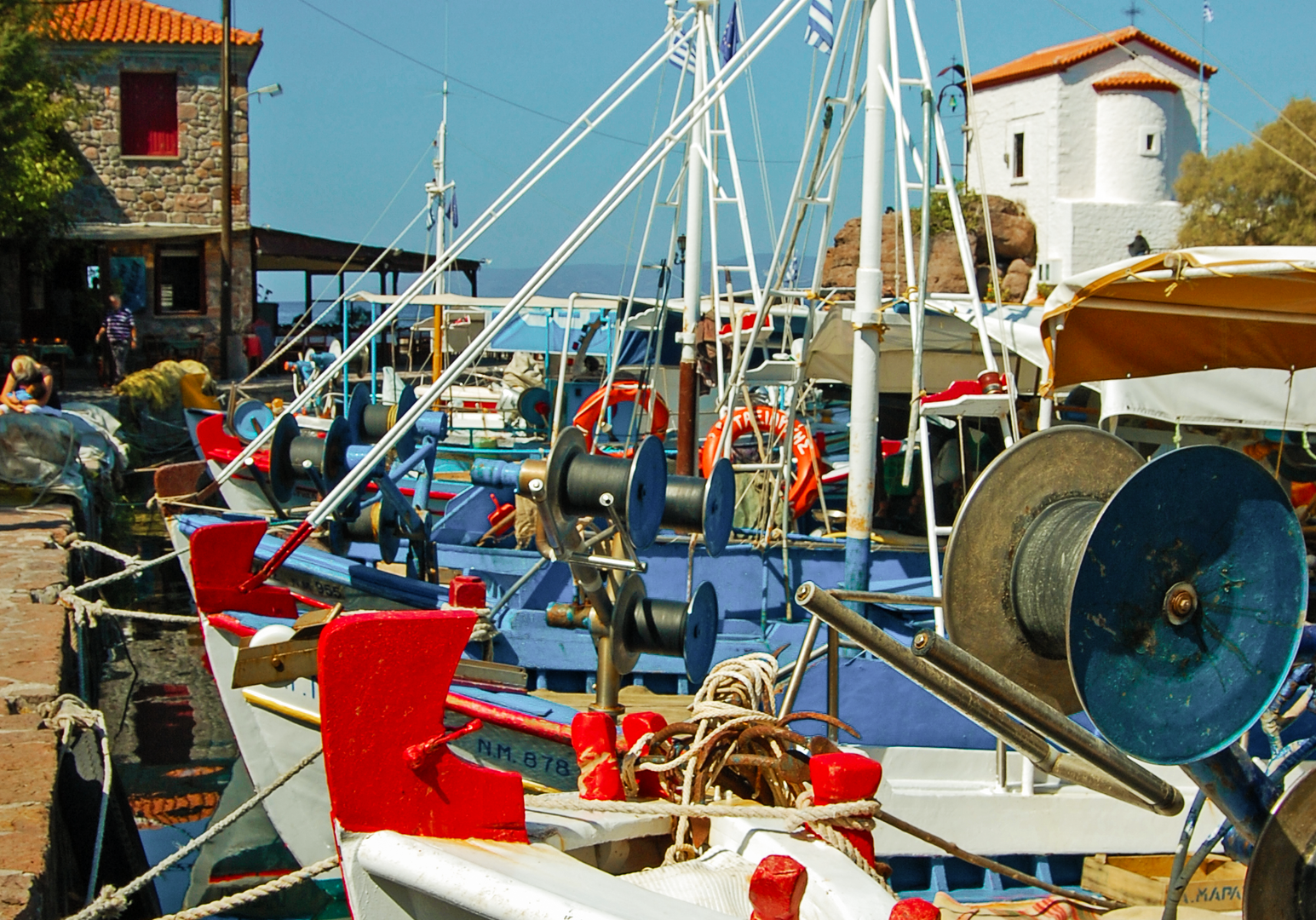 Fischerboot im Hafen vor Häusern und blauem Himmel.
