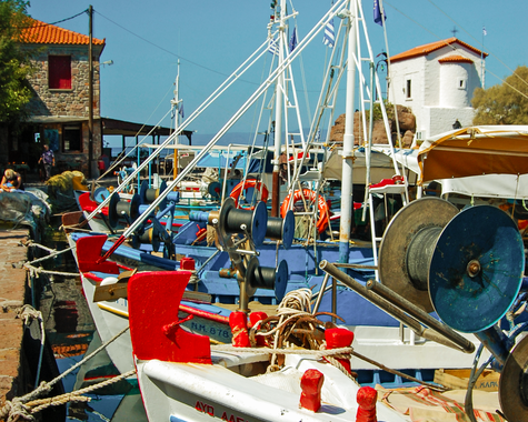 Fischerboot im Hafen vor Häusern und blauem Himmel.