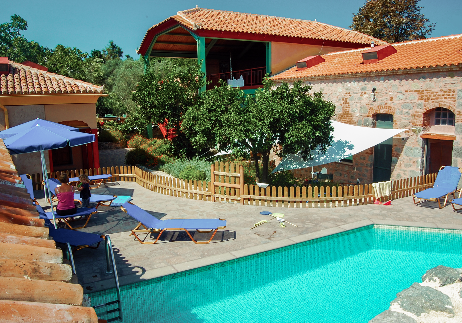 Poolbereich mit Liegen und mediterranen Gebäuden im Hintergrund.
