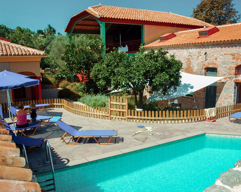 Poolbereich mit Liegen und mediterranen Gebäuden im Hintergrund.