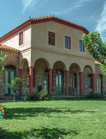 Große Gartenanlage mit Rasenfläche, Bäumen und mediterranem Gebäude.