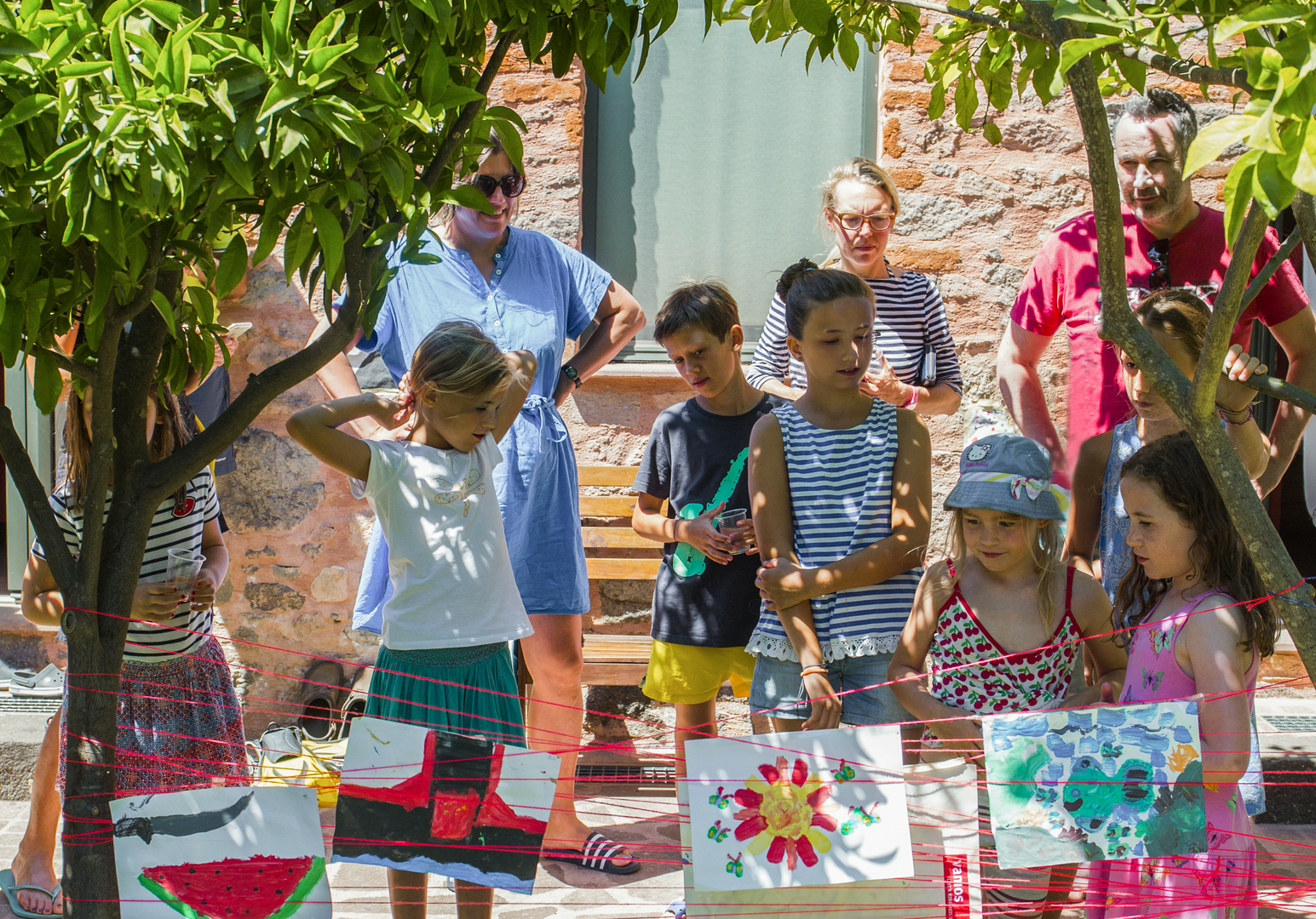 Kinder stehen und sitzen gemeinsam an bunt gedeckten Tischen im Garten.
