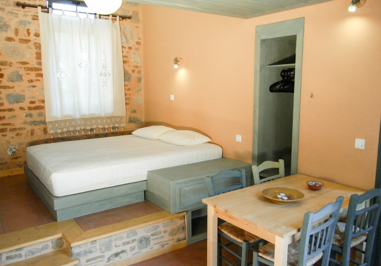 Zimmer mit Doppelbett, Esstisch und Ziegelwand