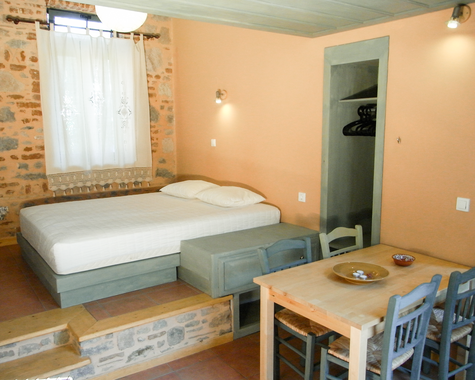 Zimmer mit Doppelbett, Esstisch und Ziegelwand