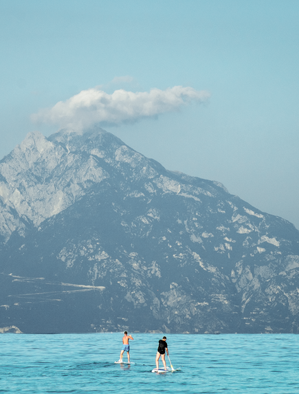Zwei Personen machen stand up paddlingvor einem großen Gebirge 