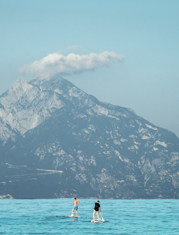 Zwei Personen machen stand up paddlingvor einem großen Gebirge 