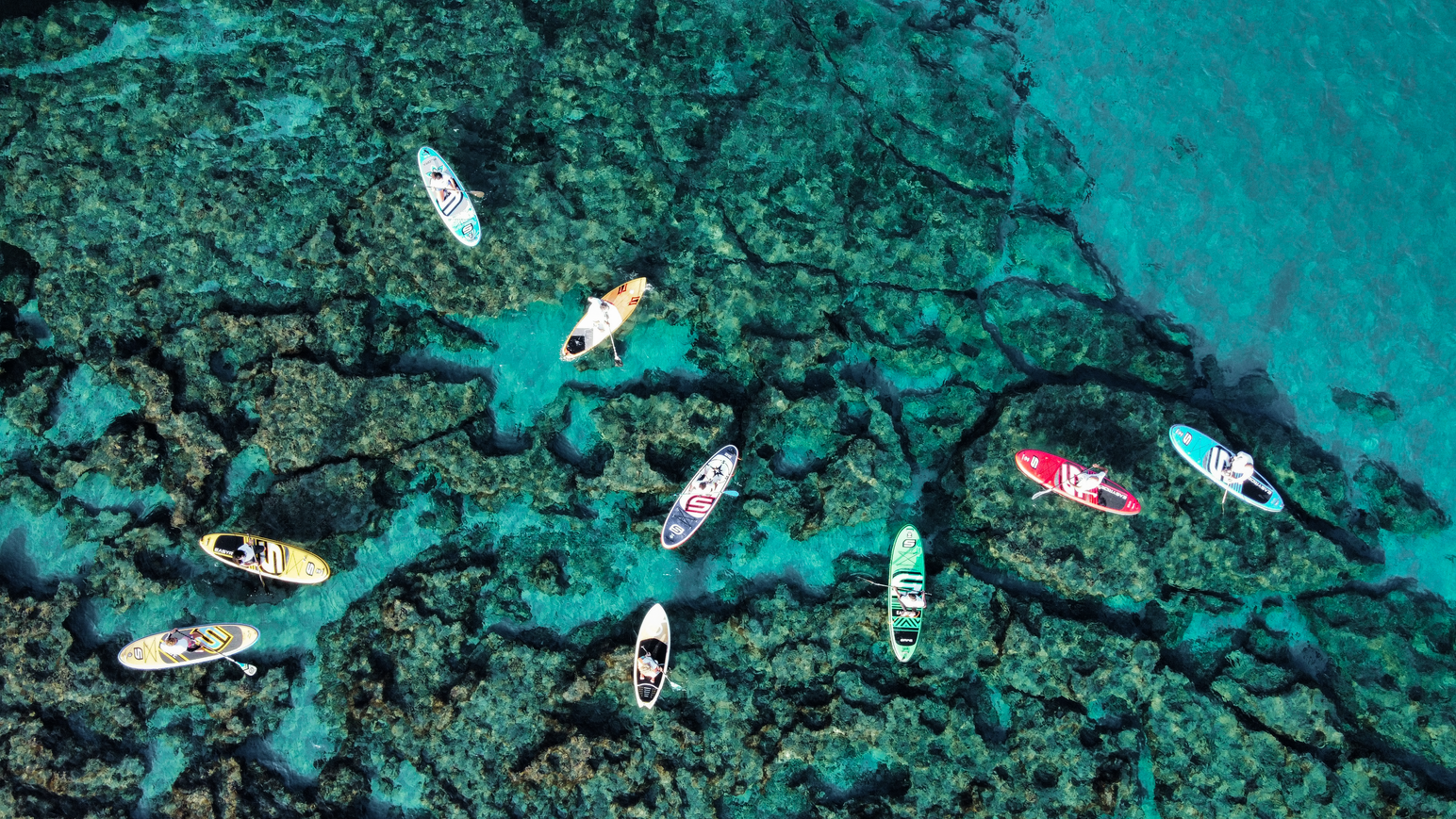 Stand-up-Paddle-Boards im klaren Wasser zwischen Felsen und Unterwasserlandschaft.