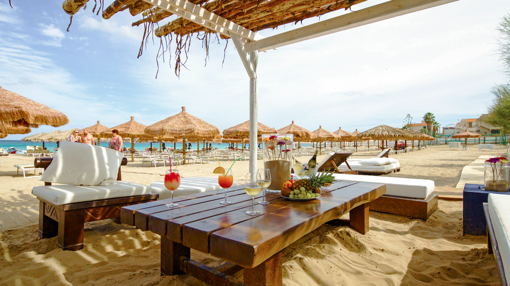 Überdachte Terrasse mit Sitzbereich und Blick auf den Strand.