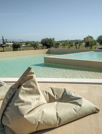 Poolbereich mit Sitzsäcken und Blick auf die Landschaft.