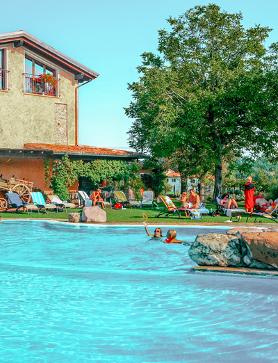 Swimmingpool vor einem Landhaus mit Garten und Liegebereich.