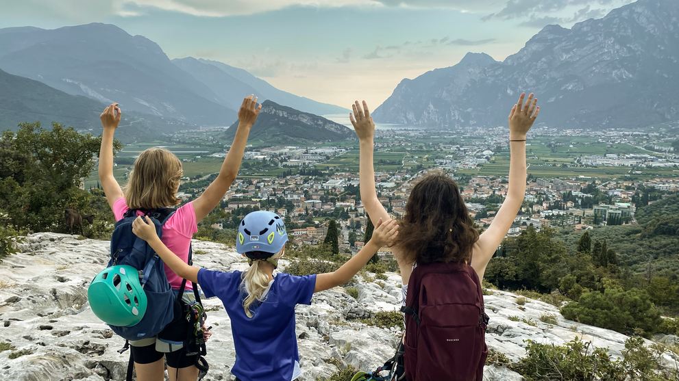 Kinder stehen auf einem Aussichtspunkt und blicken auf die Berge.
