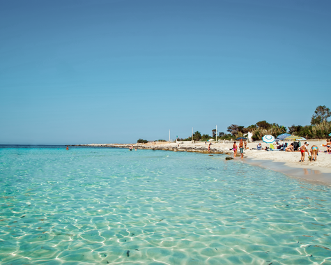 Sandstrand mit türkisblauem Meer und Blick auf die Küste.