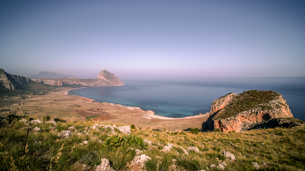 Blick auf eine Küstenlandschaft mit Bergen und Meer.