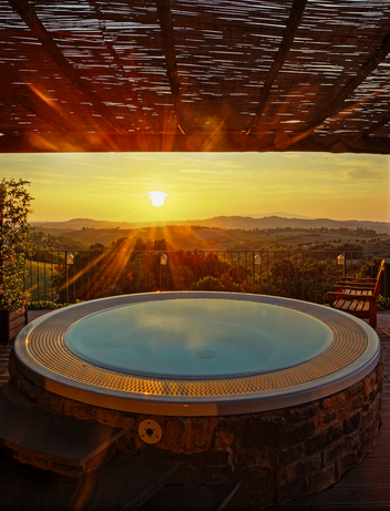 Whirlpool auf einer Terrasse mit Blick auf die Landschaft bei Sonnenuntergang.