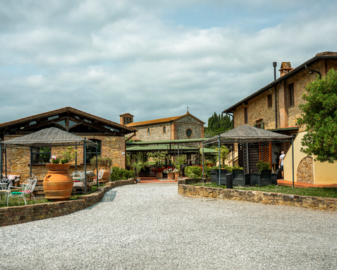 Innenhof eines historischen Landguts mit gepflastertem Platz und Sitzgelegenheiten.