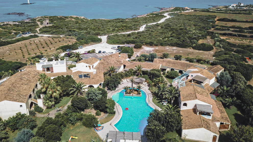Blick über eine Ferienanlage mit Pool und Meer am Horizont 