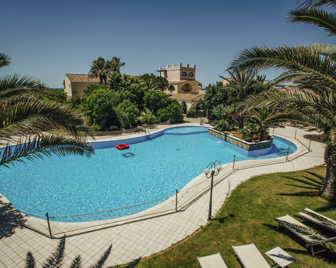Geschwungener Außenpool mit Palmen und Liegebereich in einer mediterranen Gartenanlage.