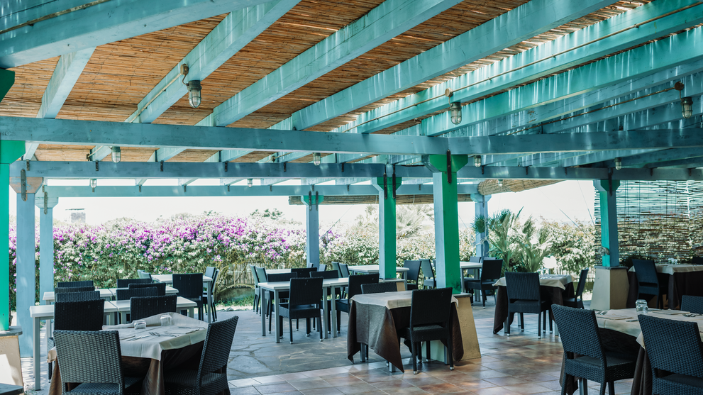 Heller Restaurantbereich mit überdachter Terrasse und Blick ins Grüne.