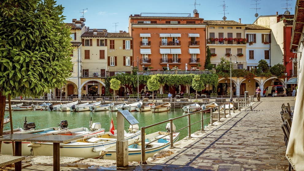 Platz mit Wasserkanal und historischen Gebäuden im Zentrum eines mediterranen Küstenortes.