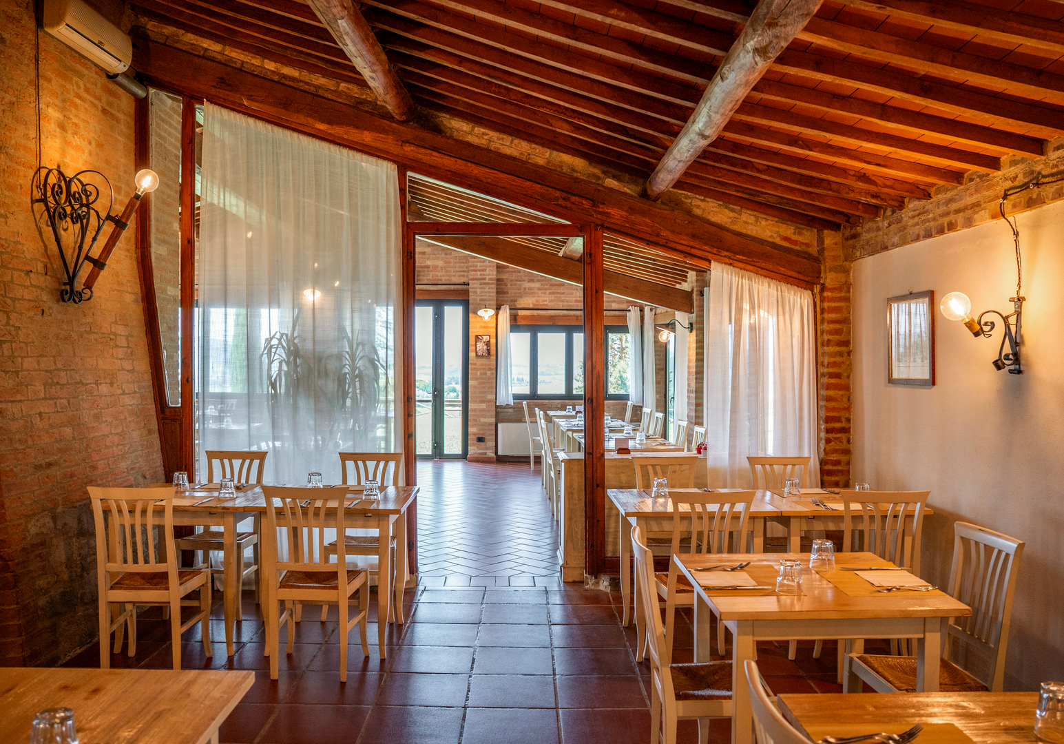 Heller Speisesaal mit Holzbalkendecke und Zugang zur überdachten Terrasse.