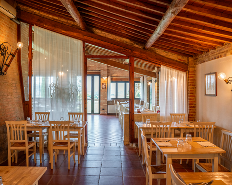 Heller Speisesaal mit Holzbalkendecke und Zugang zur überdachten Terrasse.
