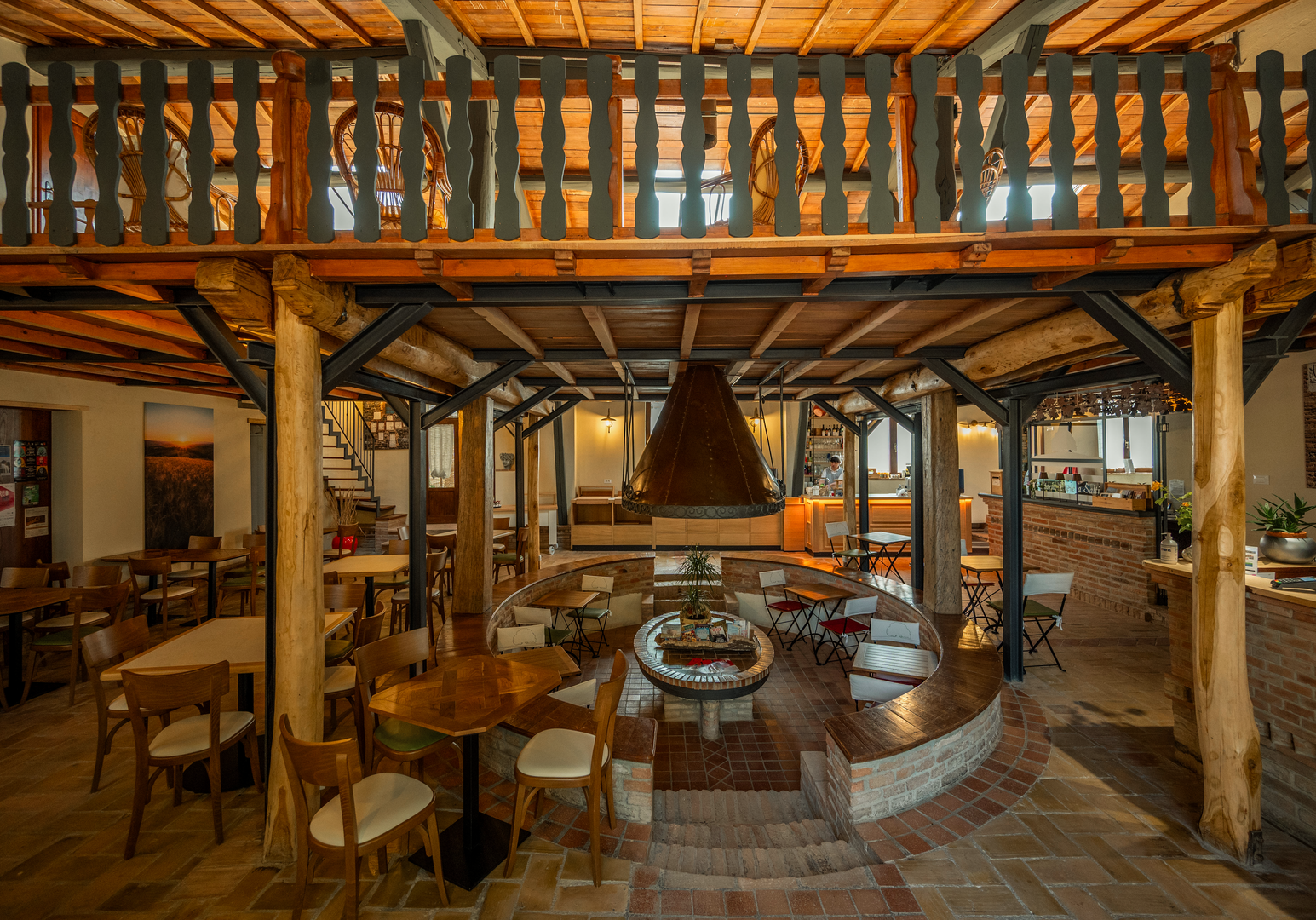 Großzügiger Aufenthaltsraum mit Holzbalken, Galerie und gemütlichen Sitzbereichen im Landhausstil.