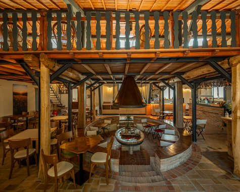 Großzügiger Aufenthaltsraum mit Holzbalken, Galerie und gemütlichen Sitzbereichen im Landhausstil.