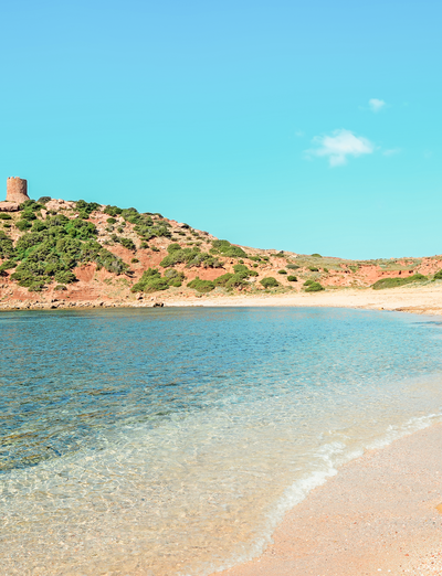 Kleine Insel mit historischem Bauwerk, umgeben von türkisfarbenem Wasser und Sandstrand.