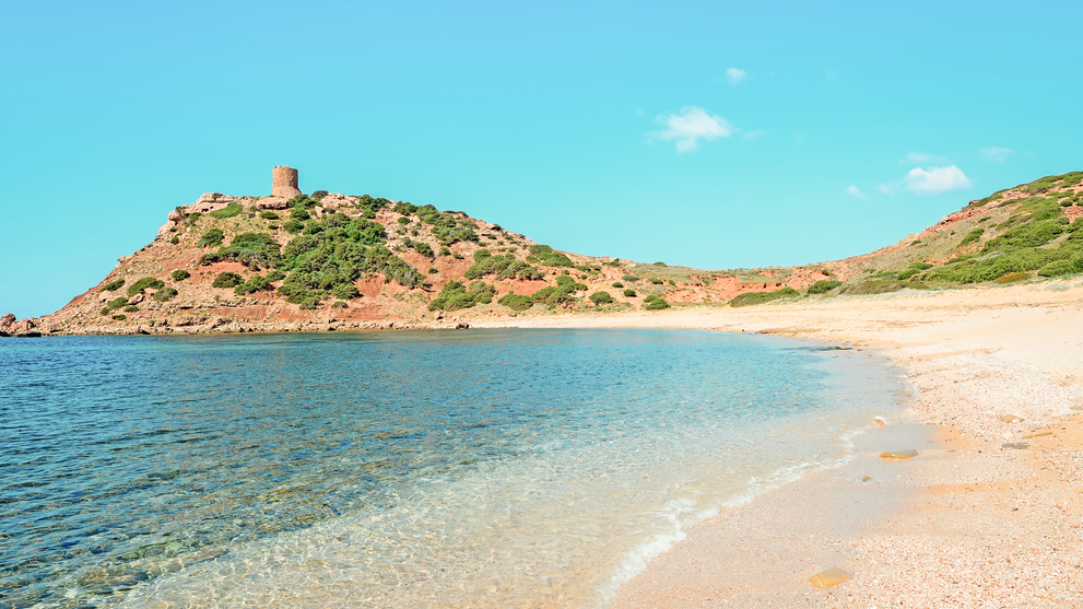 Kleine Insel mit historischem Bauwerk, umgeben von türkisfarbenem Wasser und Sandstrand.