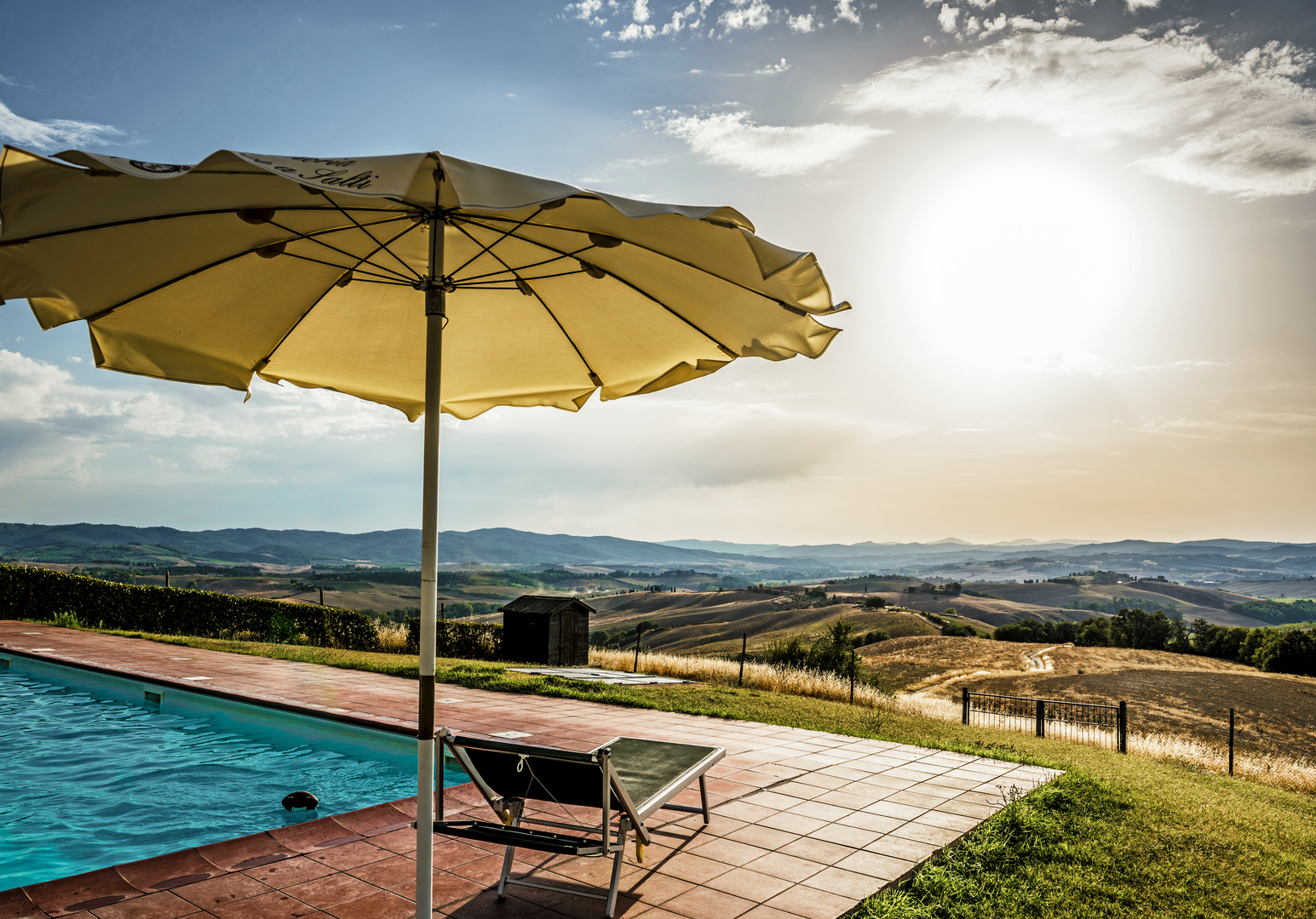 Sonnenterrasse mit Pool, Liegen und weitem Blick über die Hügellandschaft.