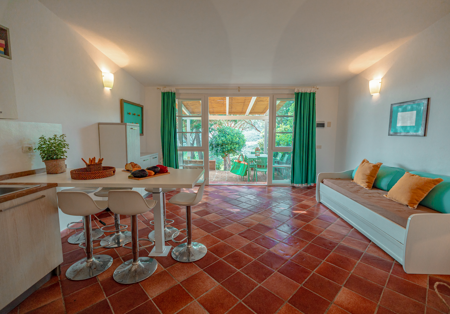 Wohnbereich mit Tisch, Barhockern, Sofa und Zugang zur Terrasse