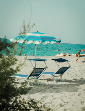 Strandabschnitt mit Sonnenschirm und Tretbooten 