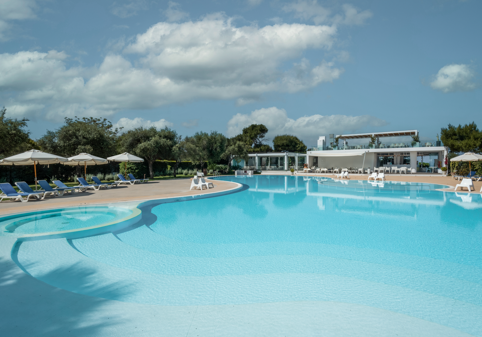 Großzügiger Pool mit ruhiger Wasserfläche und direktem Zugang zur Ferienanlage am Meer.