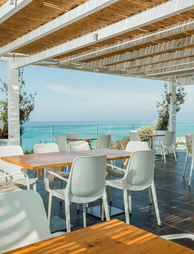 Elegante Terrasse mit gedeckten Tischen und freiem Blick auf das Meer und die umliegenden Hügel.