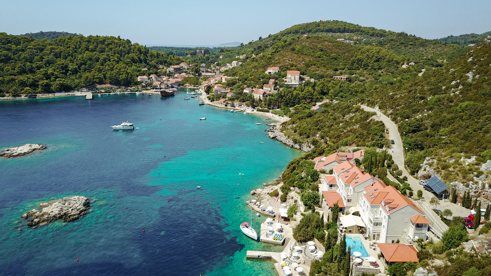 Küstenhotel an einer geschützten Bucht mit klarem Wasser und bewaldeten Hügeln.