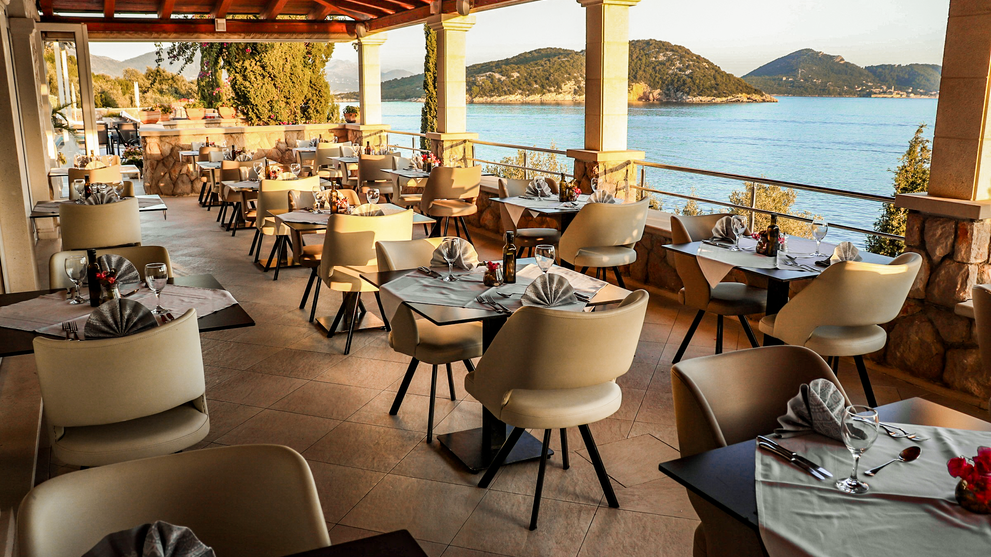 Überdachter Außenbereich eines Restaurants mit Blick auf das Meer.