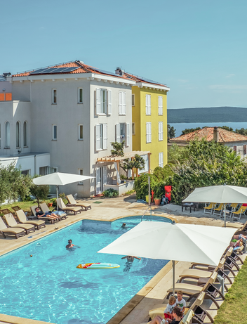 Hotelanlage mit Außenpool, Sonnenterrasse und Blick auf das Meer.